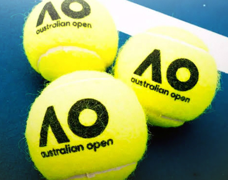 Три ярко-жёлтых теннисных мяча с логотипом Australian Open (AO) лежат на синем корте